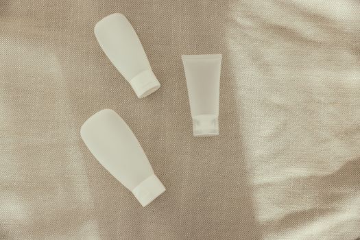 Flat lay image of minimalist plastic squeeze bottles on a textured surface.