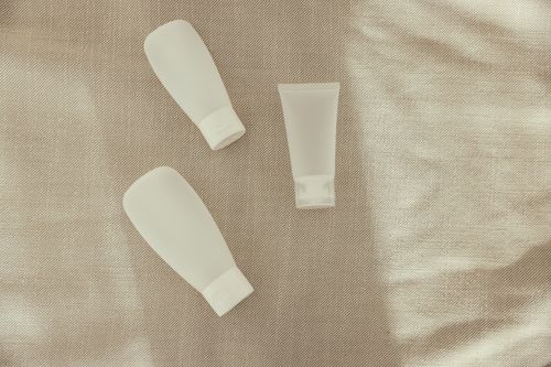 Free Flat lay image of minimalist plastic squeeze bottles on a textured surface. Stock Photo