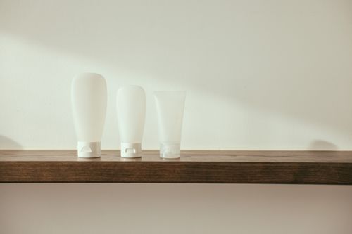 Free Minimalist product display with white bottles on a wooden shelf for branding mockup. Stock Photo