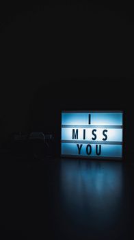 A glowing light box displaying 'I Miss You' in a dark setting, evoking emotion.