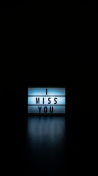 Minimalist lightbox sign displaying 'I Miss You' with a moody dark background.