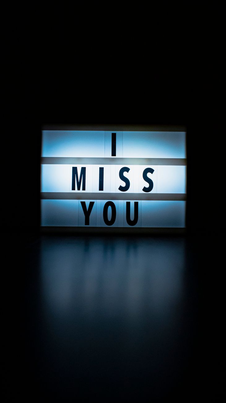 A glowing lightbox displaying 'I Miss You' against a dark background, evoking feelings of longing.