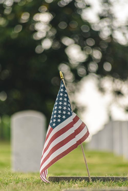 Free Patriotic close-up of American flag at a veteran's grave in cemetery. Stock Photo