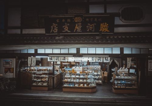 Free Charming illuminated traditional storefront in Kyoto, offering an array of goods under Japanese signage. Stock Photo