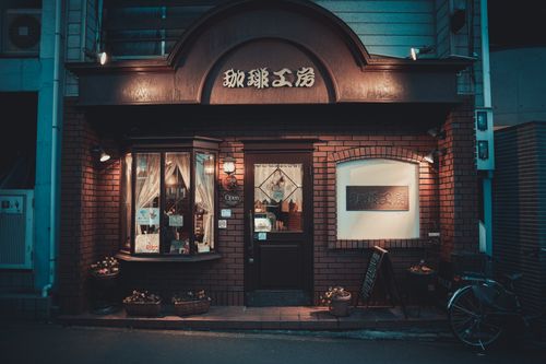 Free A quaint Kyoto cafe with a brick exterior illuminated at night, showcasing warm ambiance and inviting charm. Stock Photo