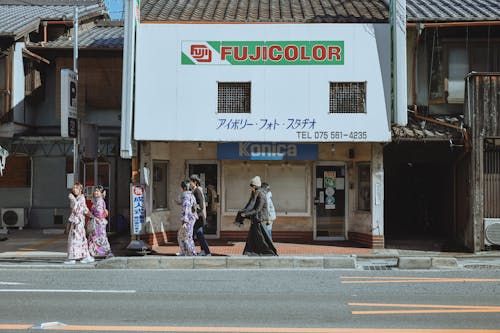 People Wearing Traditional Clothing Walking on the Sidewalk