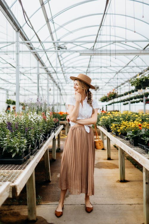 Free Woman in White Shirt and Brown Hat Standing in the Flower Shop Stock Photo