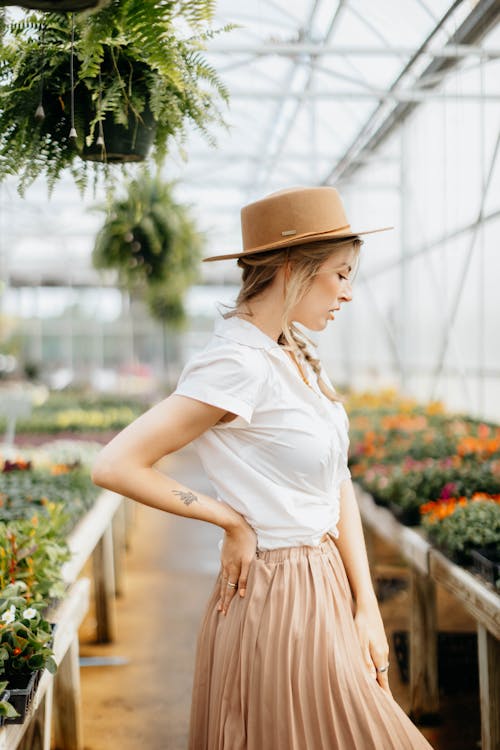 woman Wearing a Brown Hat Standing Inside a Green house
