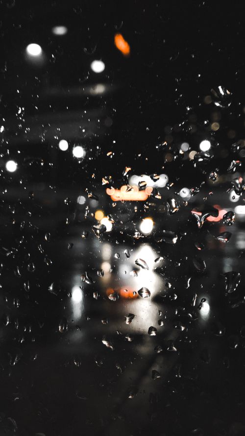 Free Raindrops on glass with bokeh of city lights at night creating a moody atmosphere. Stock Photo