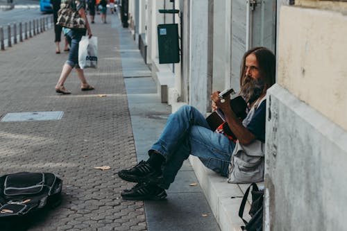 Man Playing Guitar While Sitting on Floor