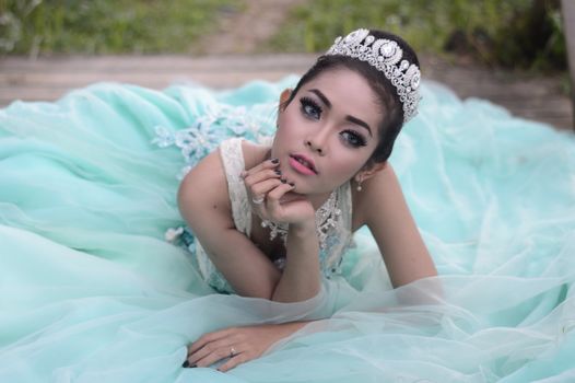 Beautiful young woman in a turquoise gown poses elegantly outdoors, embodying romance and glamour.