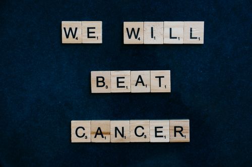 Free Motivational message 'We Will Beat Cancer' spelled out with Scrabble tiles on a dark background. Stock Photo
