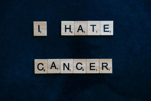 Wooden Scrabble tiles on a blue background, sharing a cancer awareness message.