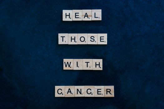 Scrabble tiles spell out a cancer awareness message on a dark blue background.
