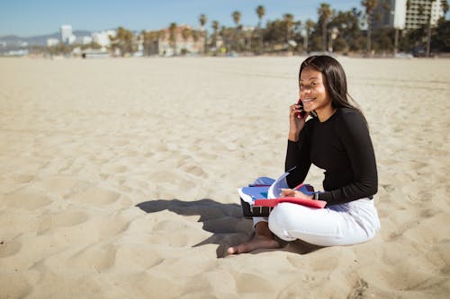 A Woman in Black Long Sleeve Shirt Sitting on the Sand