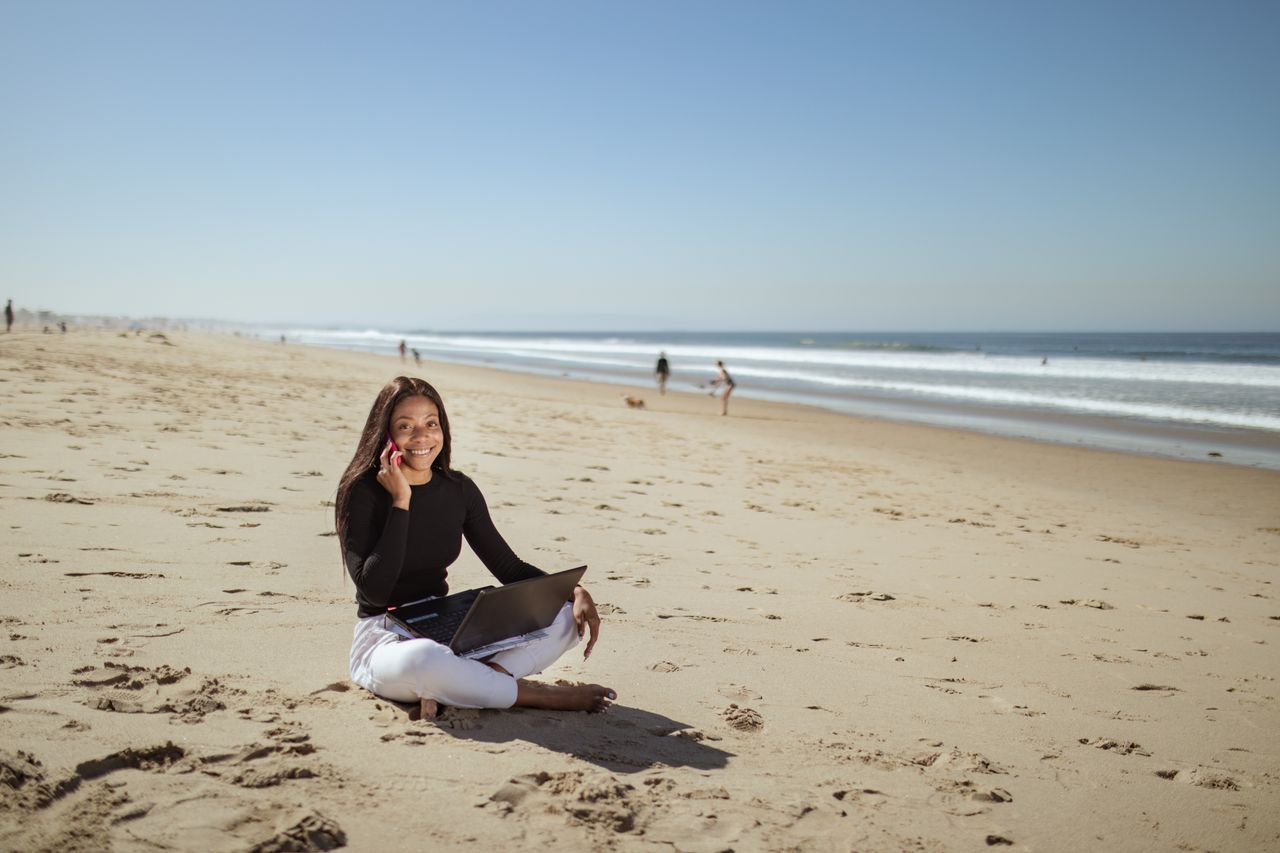 Businesswoman enjoying remote work on a sunny beach