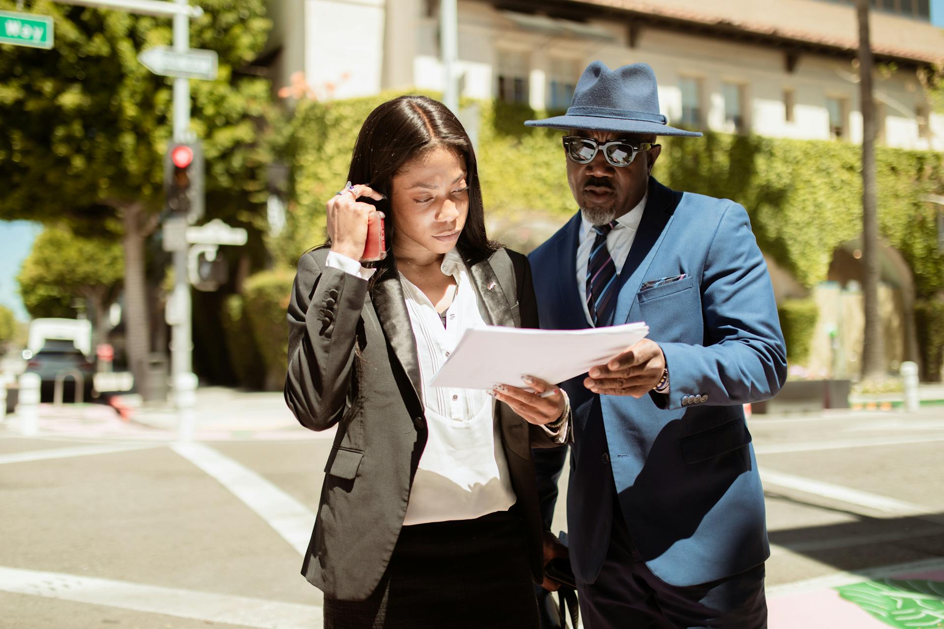 Two business professionals review documents outdoors on a sunny day, showcasing collaboration and teamwork.