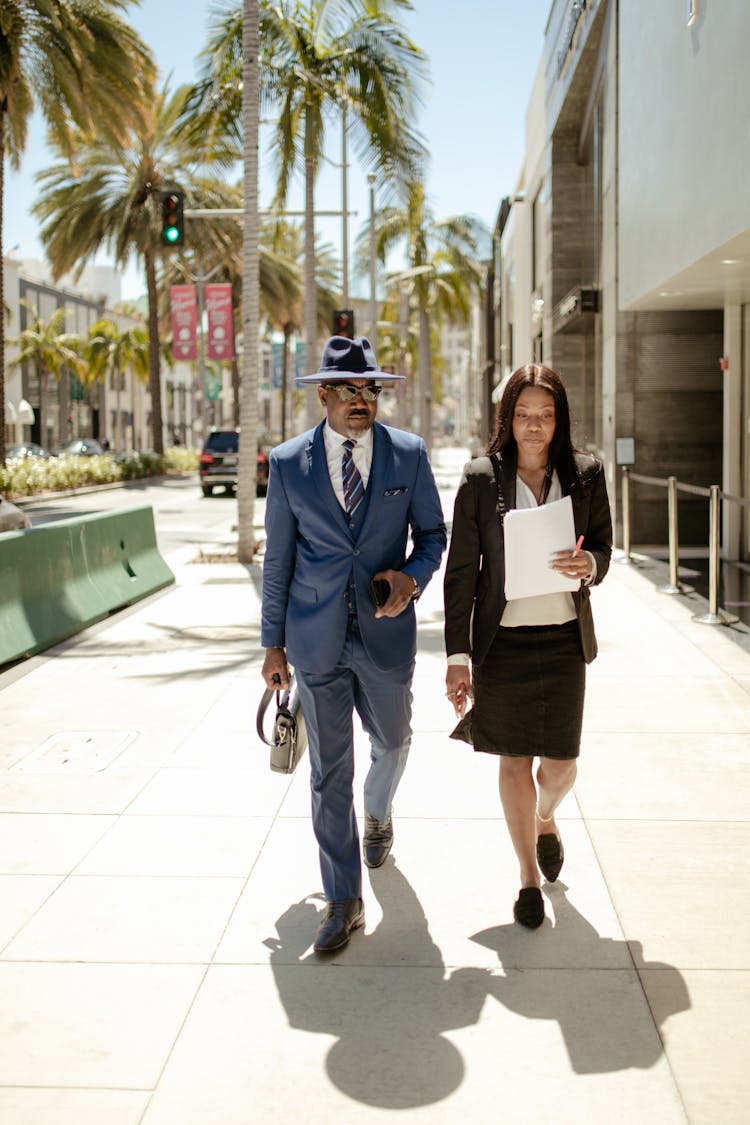 A Man And Woman Walking On The Sidewalk