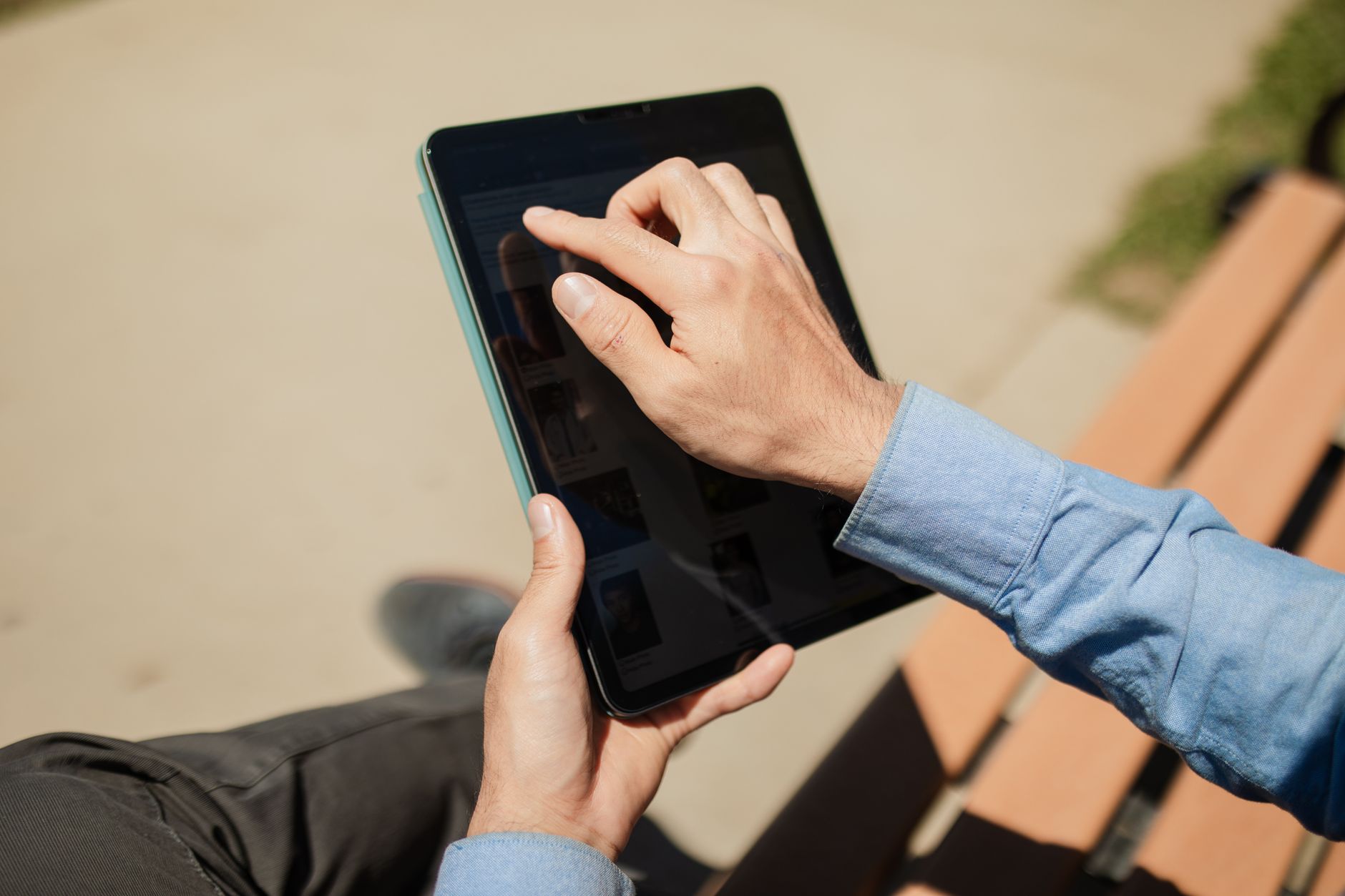 Close-up of a person using a tablet on a sunny day outdoors. Ideal for technology and lifestyle themes.