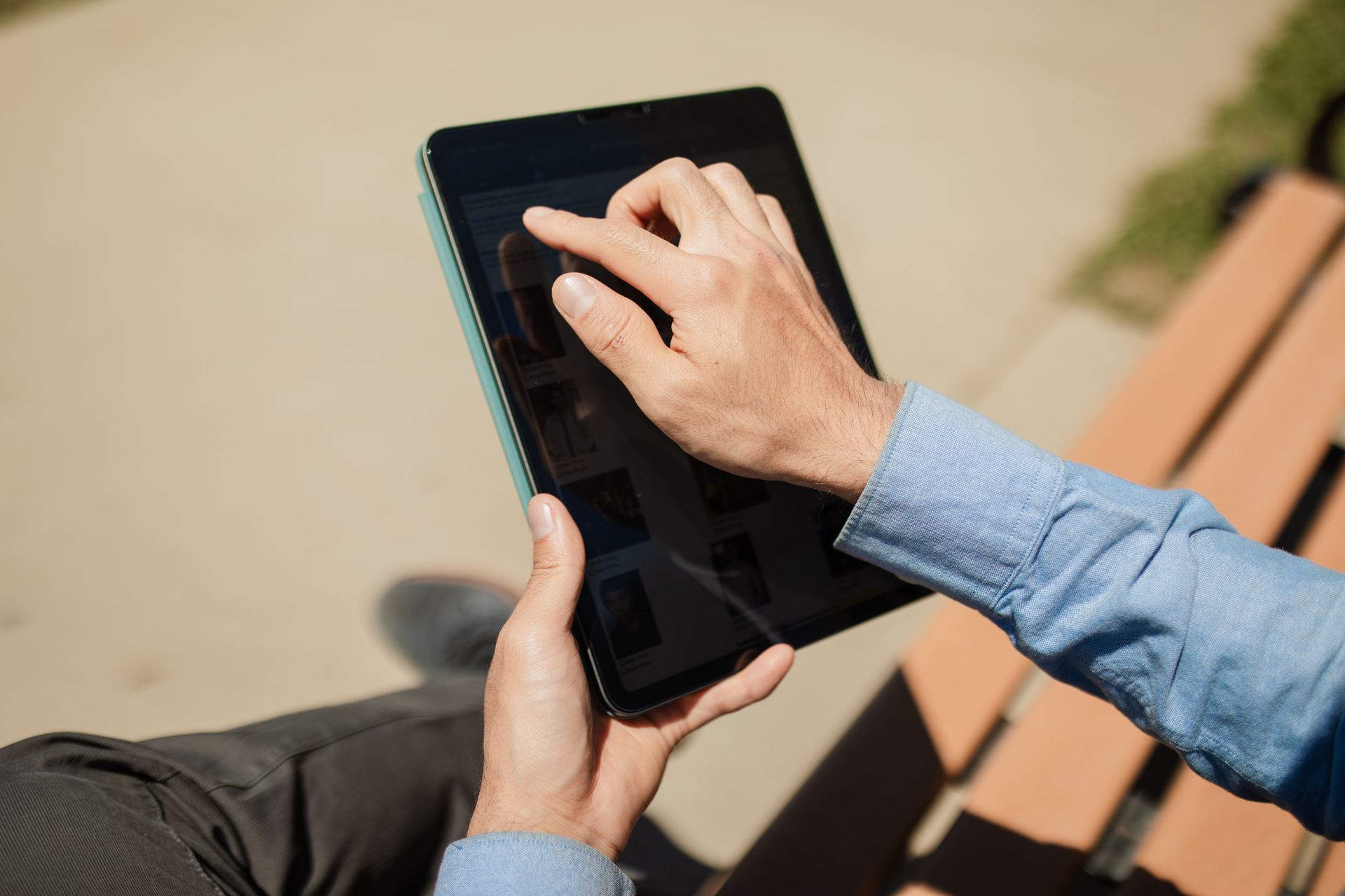 Close-up of a person using a tablet on a sunny day outdoors. Ideal for technology and lifestyle themes.