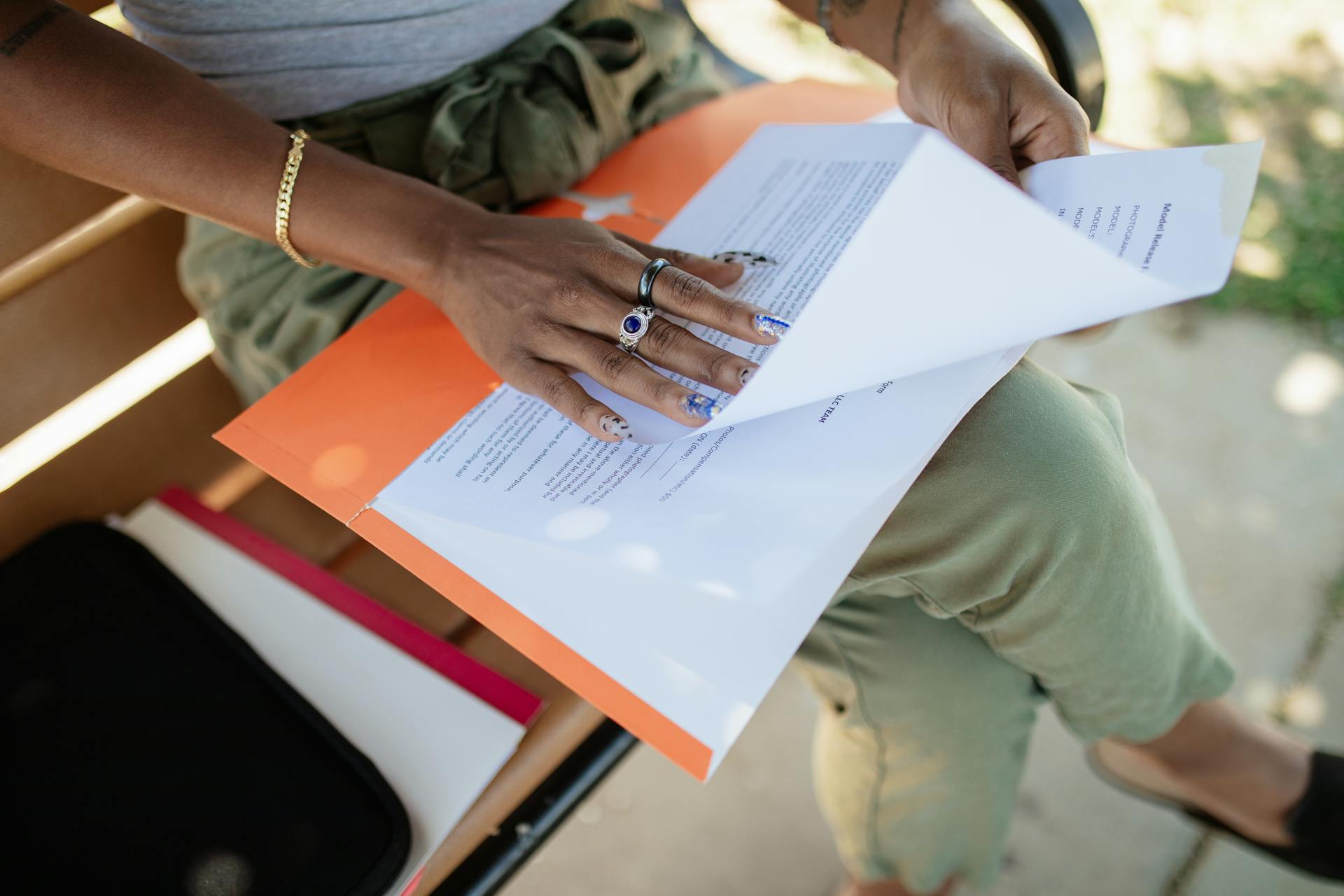 Close-up of a woman checking documents on a bench in natural light.