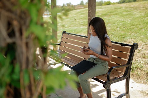 Woman Sitting on the Bench while Using Phone