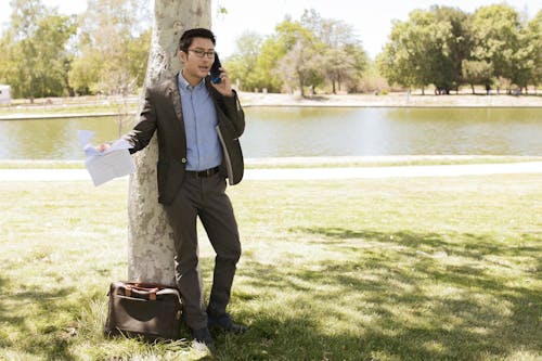 Free Man Standing in Front of a Tree While Talking on the Phone Stock Photo
