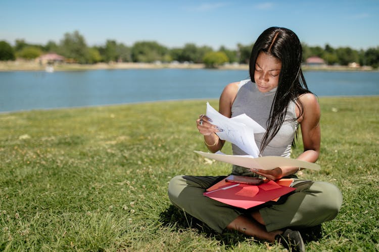 Woman Looking At Documents While Sitting On Grass