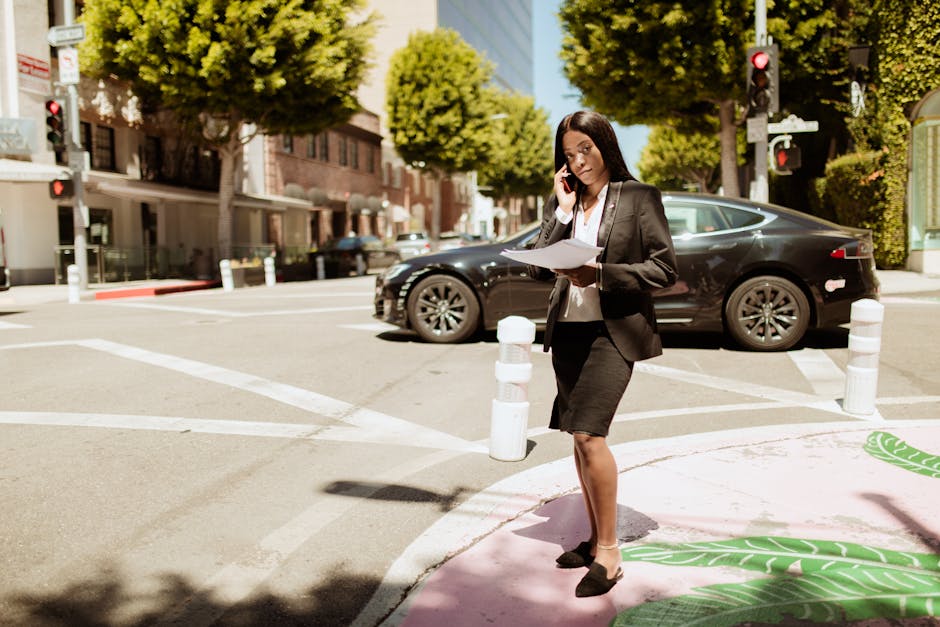 Elegant woman in business attire standing outdoors, talking on phone in cityscape.