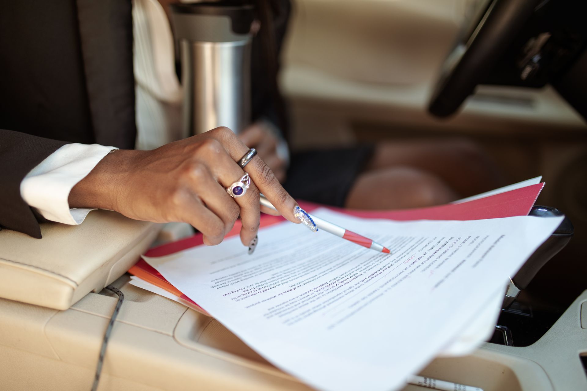 A professional reviewing documents in a car interior, focusing on hand and paperwork.
