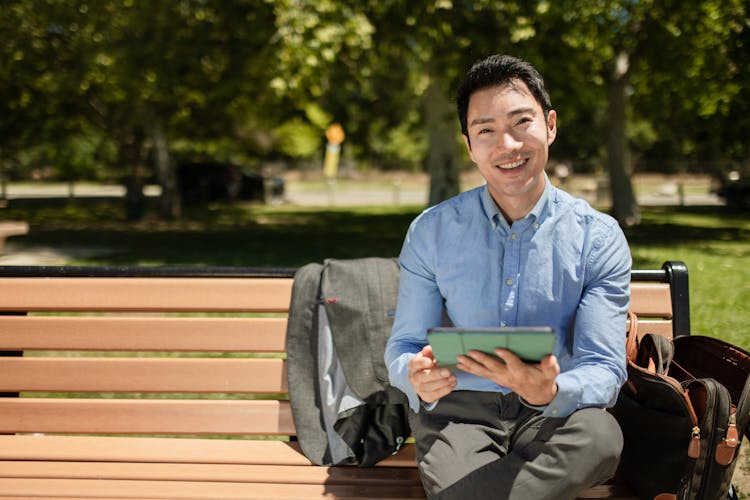 Man Smiling While Holding A Tablet 