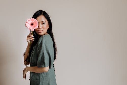 Kostnadsfri bild av asiatisk kvinna, beige bakgrund, blomma