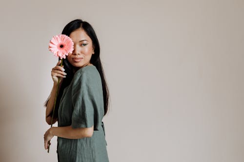 Woman in Gray Dress Holding a Pink Flower