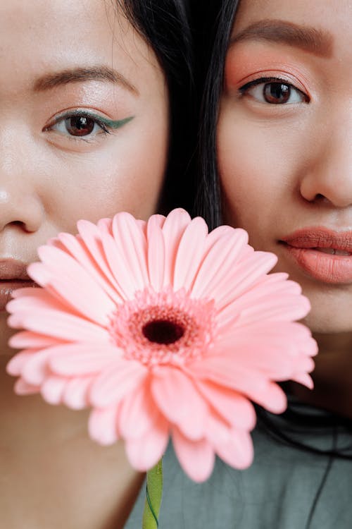 Women Posing Beside a Pink Gerbera Flower