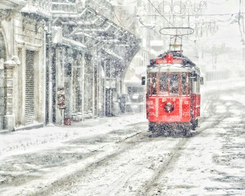 Free Classic red tram navigating a snowy street in a winter cityscape, evoking nostalgia and charm. Stock Photo