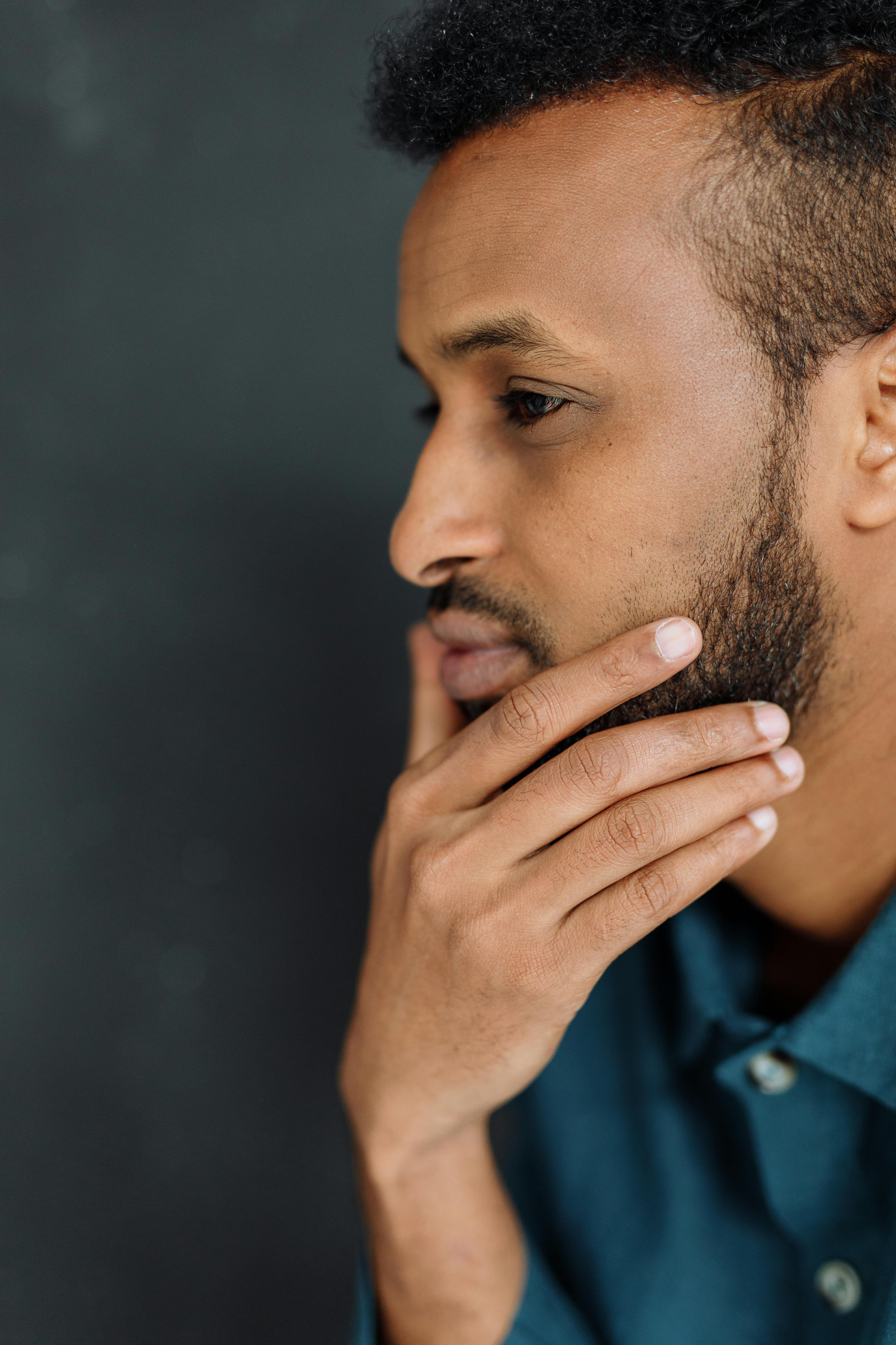 Close-up side view of a thoughtful bearded man indoors, contemplating.