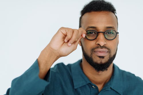 Man in Blue Long Sleeves Holding His Eyeglasses