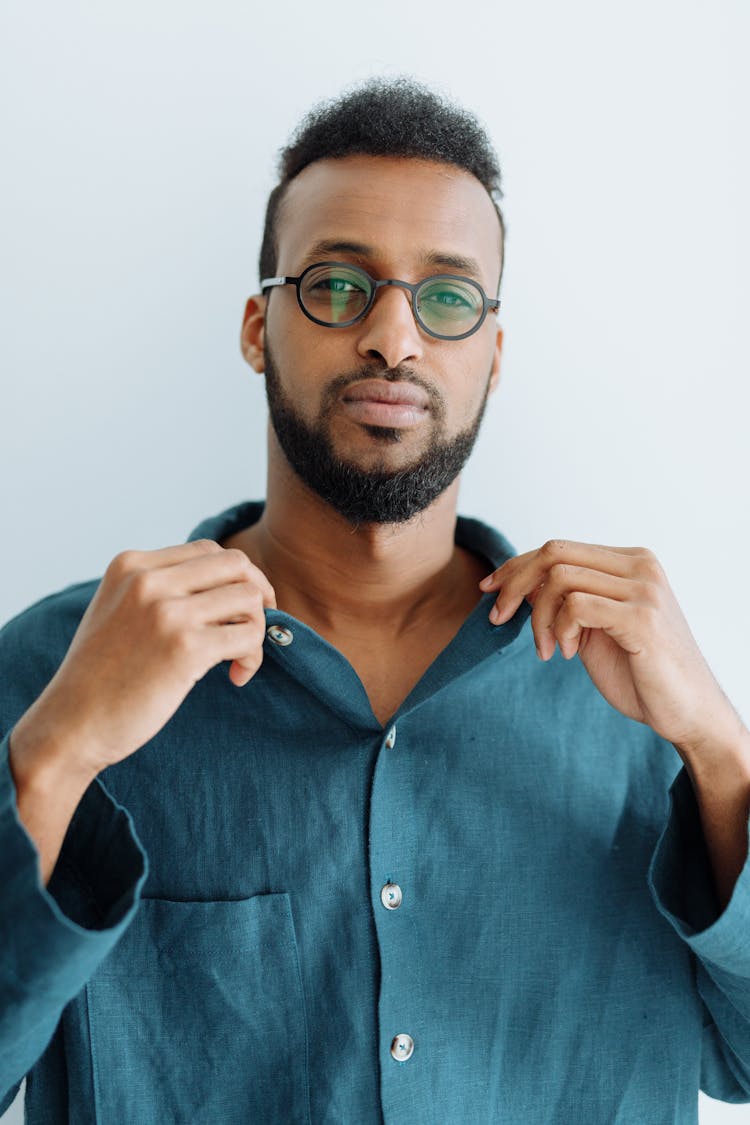 A Man In Eyeglasses Holding The Collar Of His Polo Shirt