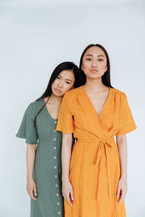 Free Two women in colorful dresses pose gracefully against a white background. Stock Photo