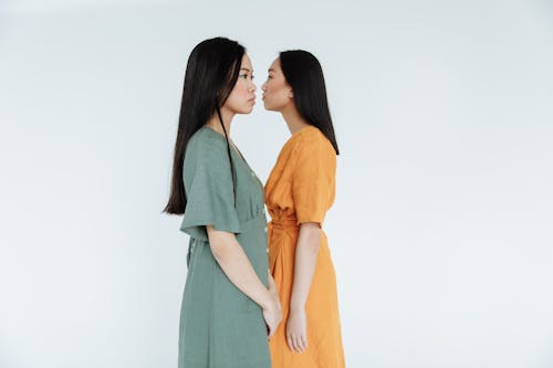 Woman in Green Dress Standing beside Woman in Orange Dress