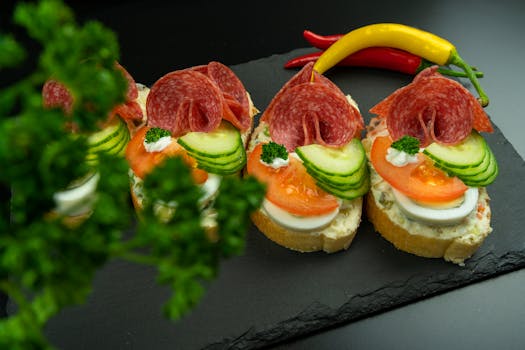 Tasty open-faced sandwiches garnished with fresh vegetables and salami slices on a slate plate.
