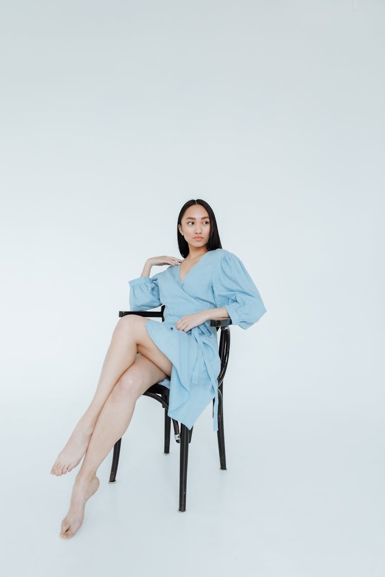 Woman In Blue Dress Sitting On A Chair