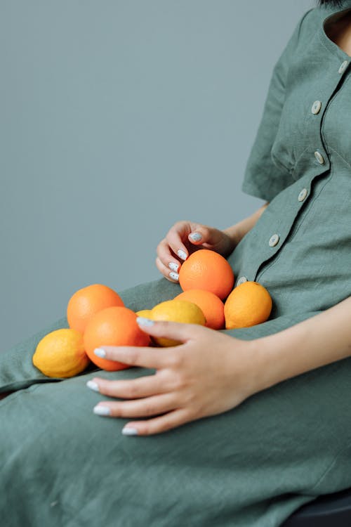 A Person holding Lemon and Orange Fruits