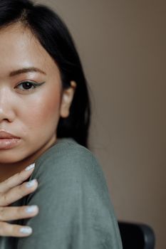 Close-up of a woman with chic eyeliner and stylish makeup in a soft setting.