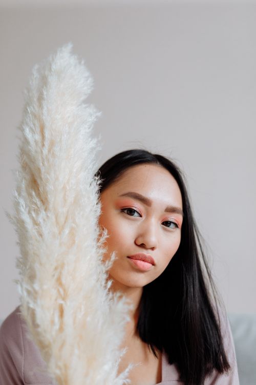 Free Beautiful portrait of an adult woman with pampas grass on a minimalist background. Stock Photo