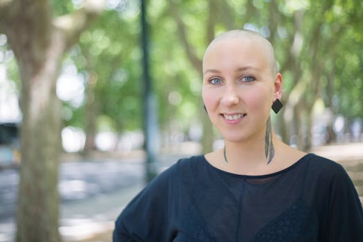 Portrait of a smiling bald woman with earrings outdoors in Portugal, showcasing confidence and individuality.