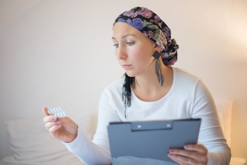 Free Woman with headscarf in bedroom reviews medication, symbolizing hope and recovery. Stock Photo