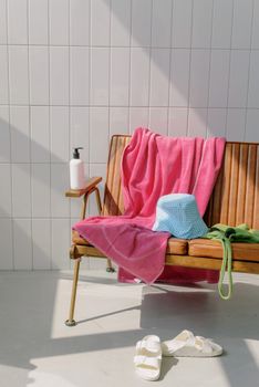 Stylish indoor setup with a chair adorned by towels, a hat, and slippers.