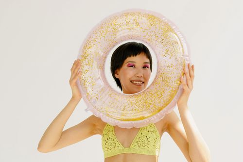 Free Cheerful woman posing with a colorful inflatable ring, enjoying summer vibes. Stock Photo