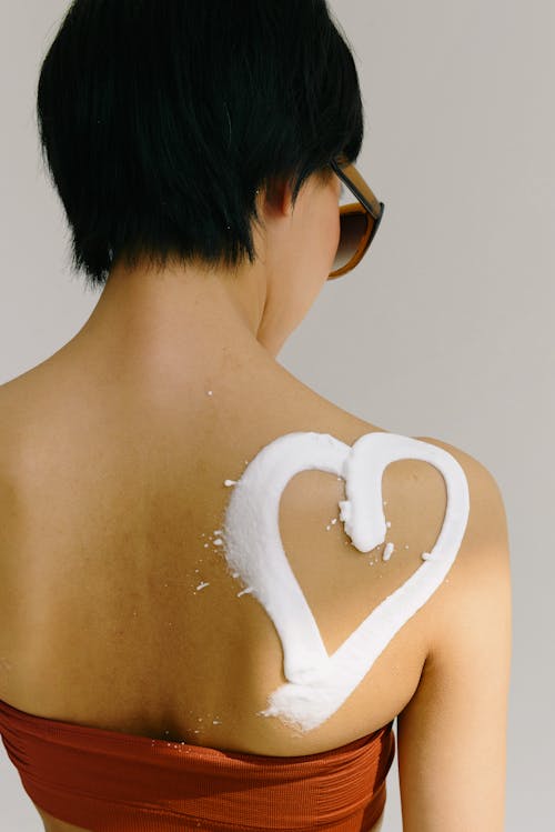 Free Woman with a Heart Painted with Sunscreen on Her Back  Stock Photo